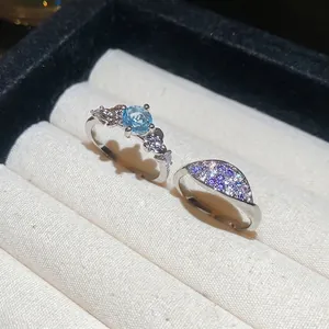 Adjustable silver flower rings with blue zircon and colorful gradient crystals in a jewelry box