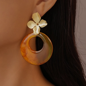 Close-up of model wearing amber resin hoop earrings with gold floral metal detail