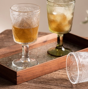Detail of vintage embossed wine glasses with leaf patterns on a rustic wooden tray
