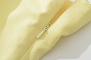 Dettaglio della cerniera invisibile su un abito da sera lungo giallo pastello