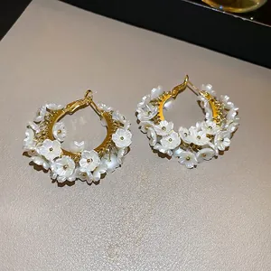 Elegant C-shaped gold hoops featuring clustered white shell flowers and pearl accents