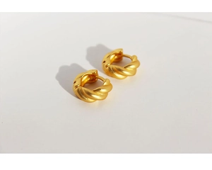 Detailed close-up of matte gold twisted hoop earrings with a textured croissant design