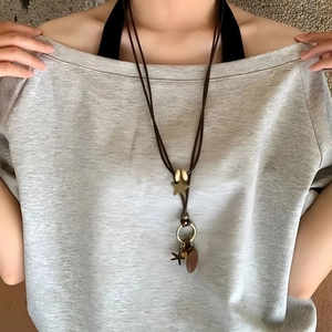 Détail d'un collier vintage en cuir marron avec pendentifs étoile et anneau en bronze