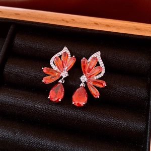 Makroaufnahme von Silberohrringen mit orangen Zirkonia auf schwarzem Samt