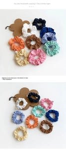 Macro detail of colorful pleated scrunchies with textured fabric and white side labels