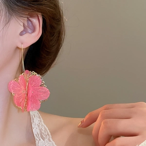 Gros plan de boucles d'oreilles fleurs roses translucides avec accents en métal doré