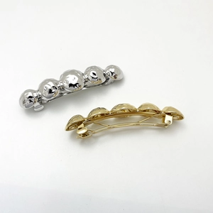 Macro detail of metallic ball spring hair clips in polished gold and silver finishes
