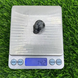 2.8cm carved natural stone crystal skull with white symbol on an electronic scale weighing 14.2g