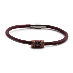 Detail of burgundy braided leather bracelet with rose gold magnetic clasp and purple stone