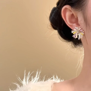 Elegant fireworks floral stud earrings with rhinestones on a female model’s ear
