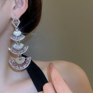 Macro shot of tiered fan-shaped drop earrings with sparkling purple crystals and fringe detail