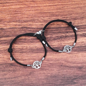 Detail of tree of life charm and heart magnetic clasps on black braided rope bracelets