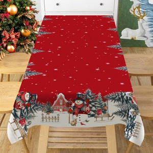 Red Christmas tablecloth with snowman and snow scene patterns on a wooden dining table