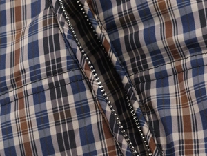 Detailed macro view of the metal zipper and blue plaid pattern on the cotton jacket