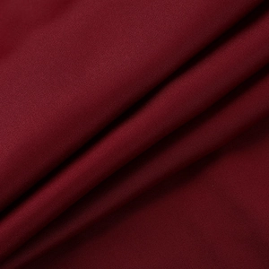 Gros plan sur le tissu en satin bordeaux montrant une texture lisse et un drapé élégant