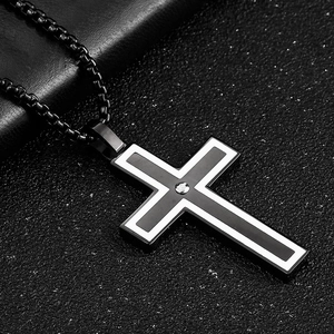 Macro shot of black cross pendant with white line detail on a textured surface