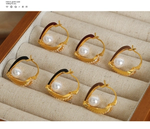 Detail of three pairs of gold hoop earrings with colorful enamel, pearls and zircons
