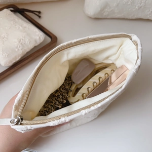 Interior view of white lace embroidery cosmetic bag showing capacity for hair accessories