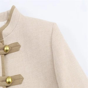 Détail du tissu en tweed beige avec des fermetures élégantes à boutons dorés