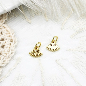 Makro-Detail des goldenen Evil-Eye-Anhängers mit Mikro-Steinen auf Spitze und Feder