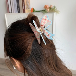Detail of butterfly hair claw with cherry print and checkerboard pattern on brown hair