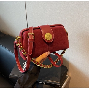 Macro detail of burgundy frosted leather doctor bag with a gold embossed buckle and chain