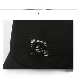Close-up of black baseball cap featuring 3D embroidered C letter with silver stitching