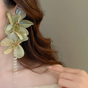 Exaggerated green lace flower earrings with crystal tassels shown on a model side view