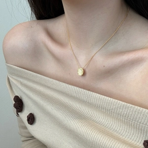 Detail of a gold S925 sterling silver coin necklace with textured star design on a model