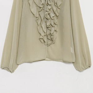 Close-up of sage green sheer chiffon blouse featuring ruffled layers and neck tie detail