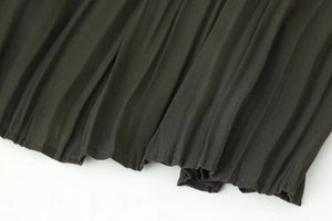 Detail shot of the dark green pleated midi dress hemline with high-quality stitching
