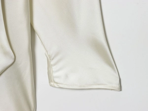 Detailed close-up of the smooth satin texture and neat stitching on off-white sleeve cuff