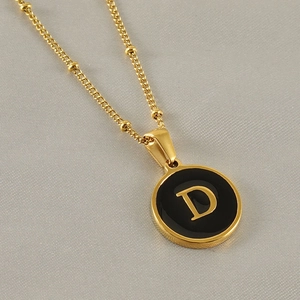 Gros plan d'un collier plaqué or 18k avec pendentif lettre D en émail noir