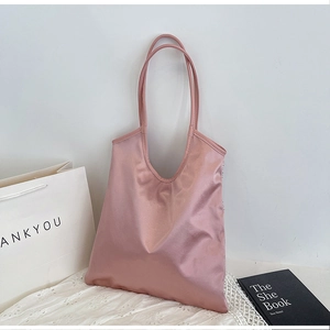 Detailed view of pink satin tote bag with thin straps on elegant embroidered white fabric
