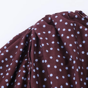 Detailed close-up of brown puff sleeves with blue polka dots and pleated shoulder seams