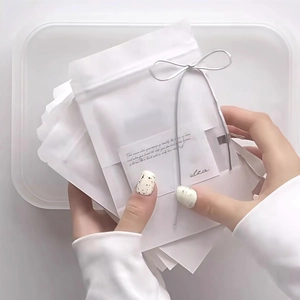 White frosted zip-lock jewelry bags with silver string tie and decorative card insert