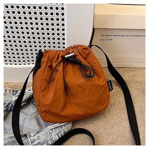 Detail of caramel drawstring bucket bag showing water-resistant nylon fabric and strap