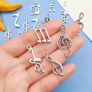 Silver musical note pendants for DIY jewelry making held in hand with starfish decor