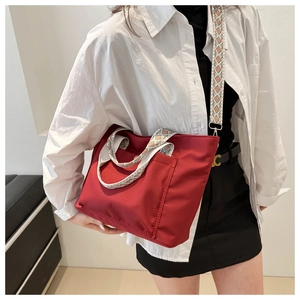 Detail of red nylon tote bag with colorful geometric woven wide shoulder straps