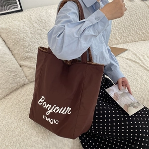 Detail of coffee brown tote bag with Bonjour magic print and plush lining texture