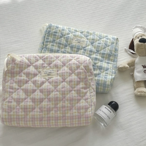 Close-up of quilted plaid cosmetic bags with diamond stitching and ribbon zipper pull