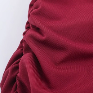 Close-up of red knitted long dress showing fine fabric texture and pleated details