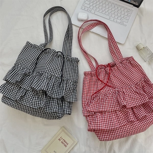 Flat lay of plaid ruffle tote bags with drawstring detail and lifestyle props
