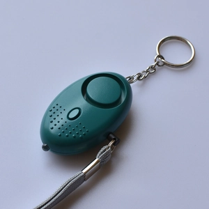 Detail view of a green personal safety alarm featuring a built-in LED light and metal keychain