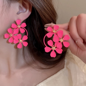 Close-up of hot pink floral mesh earrings with golden stamens and pearl accents