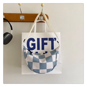 Close-up of blue and white checkered crescent bag hanging on a wooden hook in a home setting