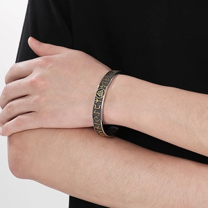 Detail of vintage Viking runes and Valknut symbol on men's stainless steel cuff bracelet