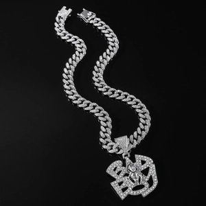 Macro shot of silver Cuban chain necklace with iced-out B letter spider crown pendant