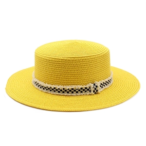 Gros plan d'un chapeau canotier jaune avec ruban damier noir et blanc à bords effilés