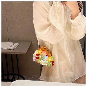 Detail of floral woven shell bag with wooden clasp and elegant pearl handle strap